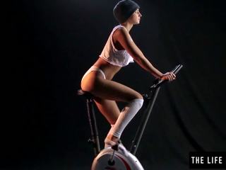 Adorável suado jovem grávida a esfregar um exercise bike assento.