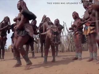 Afrikansk himba kvinnor dansa och gunga deras saggy tuttarna runt