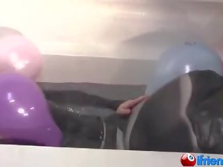 Lateksi pukeutunut tyttö kanssa ilmapallot sisään a kylpyamme